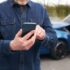 A man typing a phone number into his iPhone to call a personal injury lawyer for advice after causing a car accident without insurance.